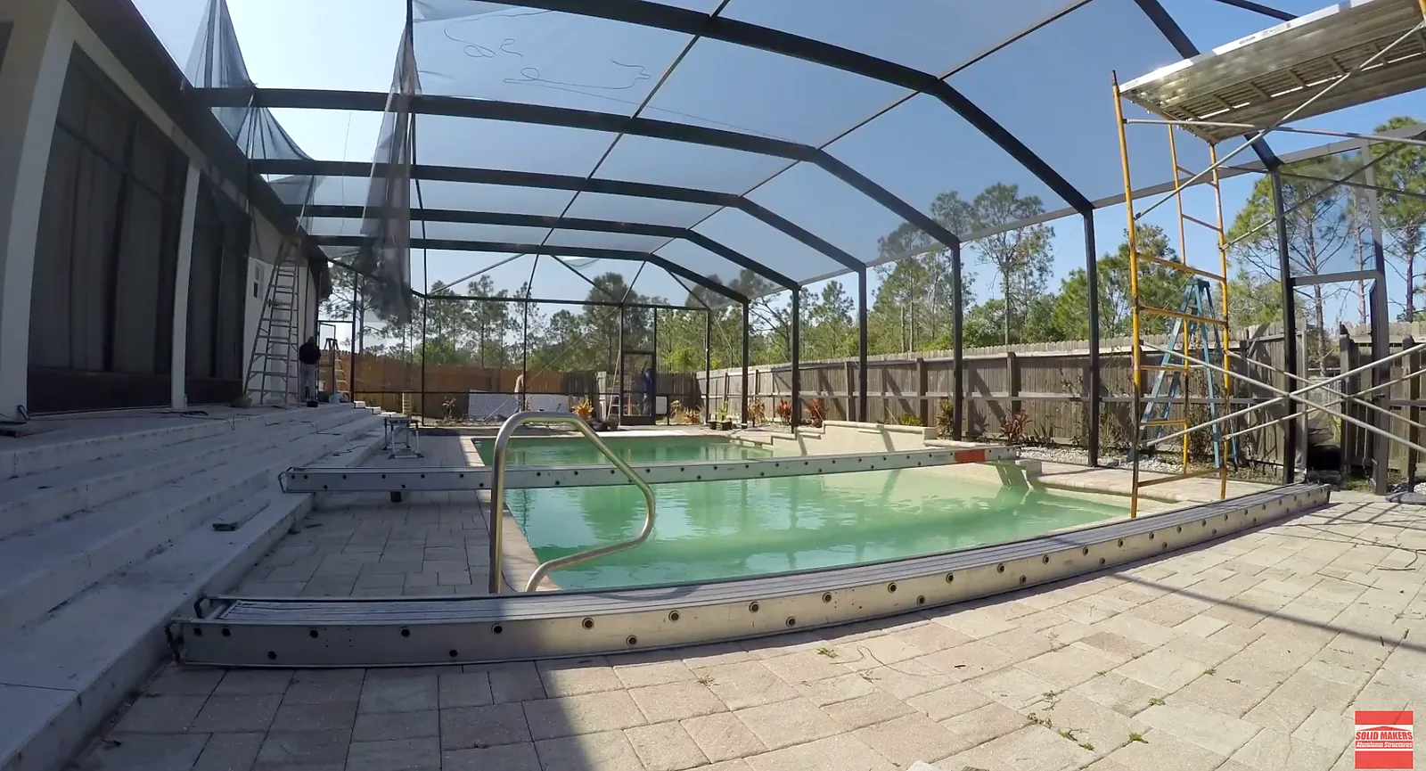 Full pool cage rescreen in progress in Lehigh Acres Florida with scaffolding and upper panel work